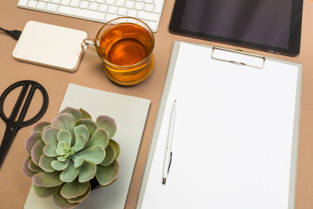 istock office desk table with tablet  clipboard keyboard notebook tea cup disc and scissors. Mock up template . Top view.- Image 1138985491