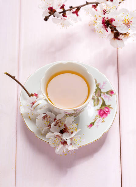 istock Cup of tea and spring flowers (blooms of an Apricot) on a light pink wooden table. 1138986162