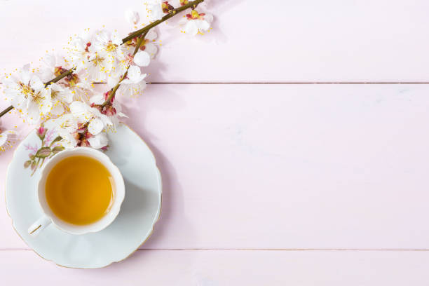 istock Cup of tea and spring flowers (blooms of an Apricot) on a light pink wooden table. 1138986428