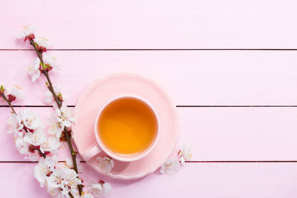 istock Cup of tea and spring flowers (blooms of an Apricot) on a light pink wooden table. 1138986527