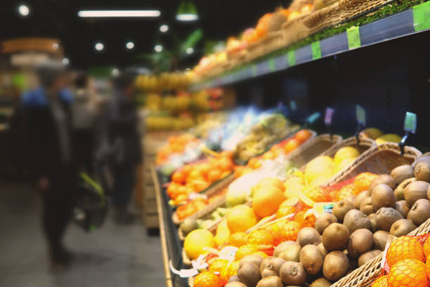 Background of supermaket with different fruits. Blurred image of customers choosing fruits.