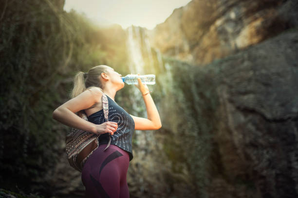 istock Young female drinking water in nature under waterfall. 1138992403