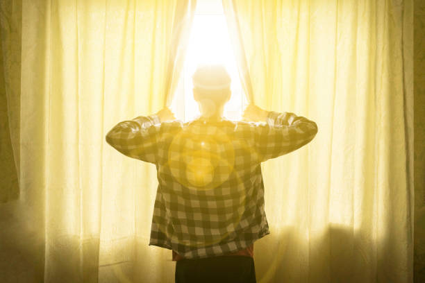 istock young male opens curtains window in the morning with light rays come in d 1139007833