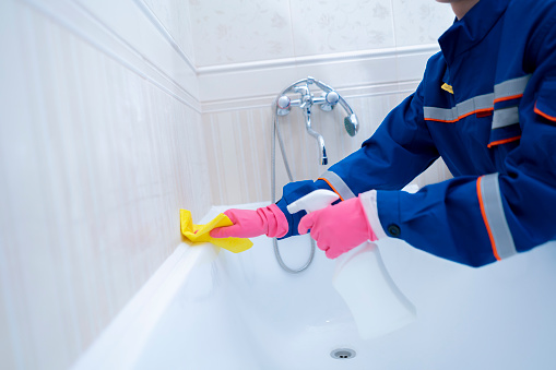 working cleaning service staff in home bathroom