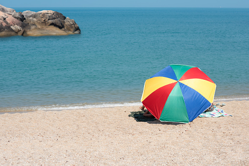 multicolor beach parasol gamp umbrella pin on the sea beach at sunlight of day time, protect sunshade for tourist in summertime, travel on the sea beach in vacation long weekend