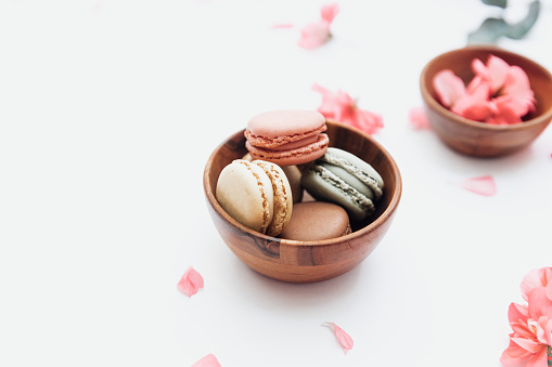 Beautiful variety of macaroons on wooden bowl. Stylish arrangement sweet. Flat lay, top view
