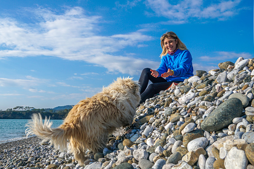 Woman playing with dog sitting on pebbles.