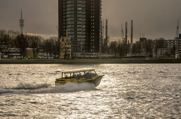 Rotterdam, The Netherlands, December 12, 2018: watertaxi travelling with high speed on the river Nieuwe Maas with Charlois neighbourhood in the background