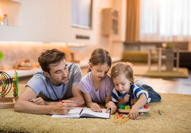 istock Young father and small kids drawing on carpet at home. 1139034522