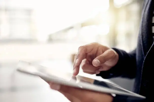 Closeup shot of an unrecognizable businessman using a digital tablet in an office