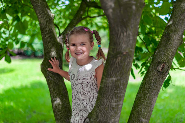 little beautiful girl is playing and posing on the tree