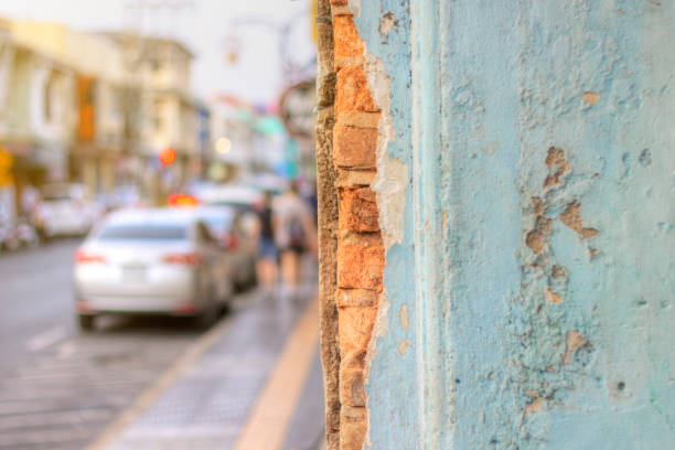 Grunge light blue walls that the cement was broken until they saw the bricks inside. The background is street and walkway. Concept for pasting posters or text on the wall.