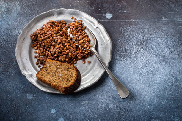 Lentils on plate Lentils with bread on a metal plate with a spoon in a grunge setting. Poor and lacking nutrition prison meal stock pictures, royalty-free photos & images