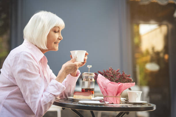 istock Old woman sitting outside and drinking tea 1139049303