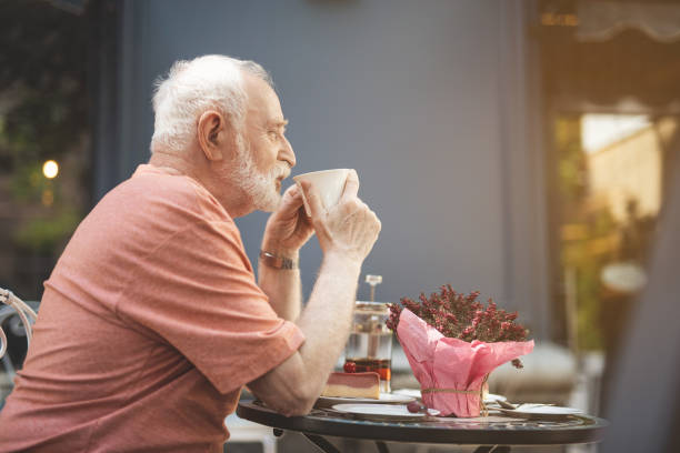 istock Old man having hot drink in cafe outside 1139049306