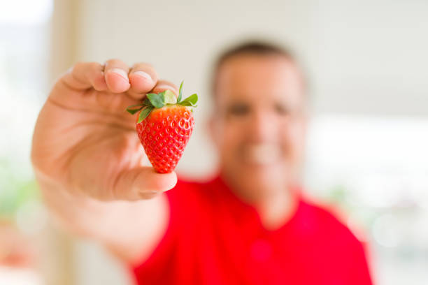Close up middle age man holding strawberry