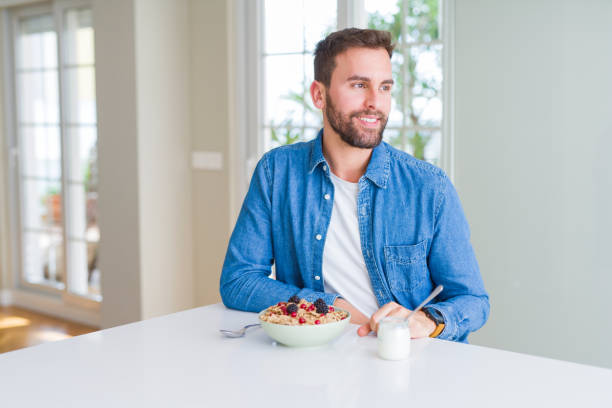 istock Handsome man eating cereals for breakfast at home looking away to side with smile on face, natural expression. Laughing confident. 1139054621