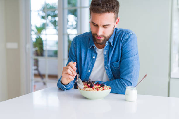 istock Handsome man having breakfast eating cereals at home and smiling 1139054709