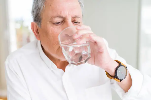 Photo of Handsome senior man drinking a fresh glass of water at home