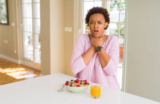 젊은 아프리카계 미국인 여자 집에서 아침에 건강 한 아침 식사 소리와 다치거나 때문에 고통 스러운 strangle. 건강 문제. 및 자살 개념. - choking 뉴스 사진 이미지