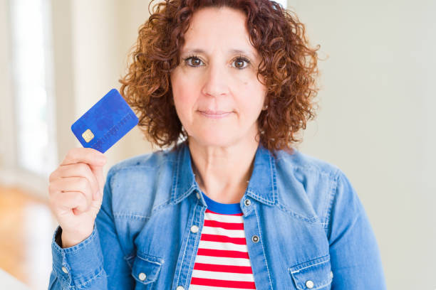 istock Senior woman holding credit card as payment with a confident expression on smart face thinking serious 1139059752