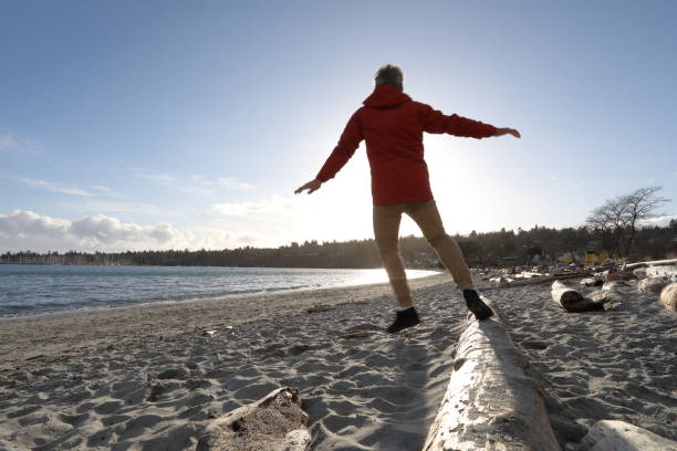 istock Low angle view of man balancing on log on beach 1139062144
