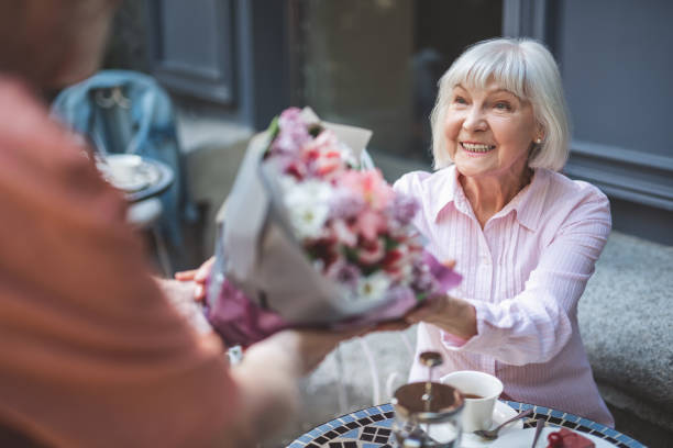 istock Smiling elderly female meeting man with flowers 1139063723