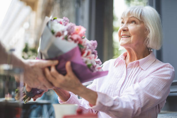 Amazed mature lady taking flowers from male