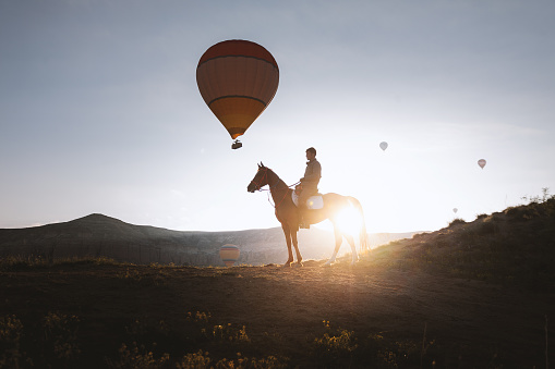 Horseback rider in the morning with balloons on cappadocia.