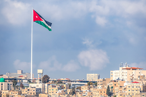 02/18/2019 Amman, Jordan, the flag of Jordan on the background of the gloomy sky walks in the wind above the capitals of the capital of the Middle Eastern state