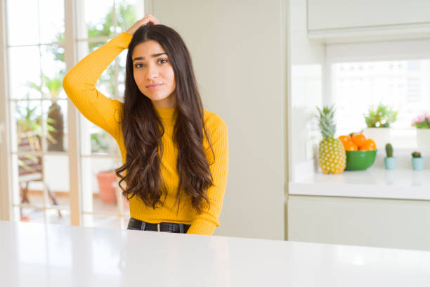 istock Young beautiful woman at home on white table confuse and wonder about question. Uncertain with doubt, thinking with hand on head. Pensive concept. 1139065708