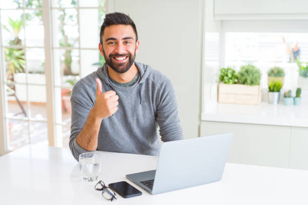 istock Handsome hispanic man working using computer laptop happy with big smile doing ok sign, thumb up with fingers, excellent sign 1139067253