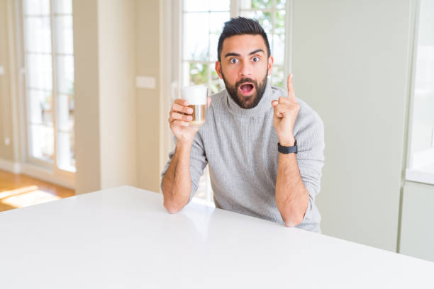 istock Handsome hispanic man drinking a cup of coffee surprised with an idea or question pointing finger with happy face, number one 1139067357