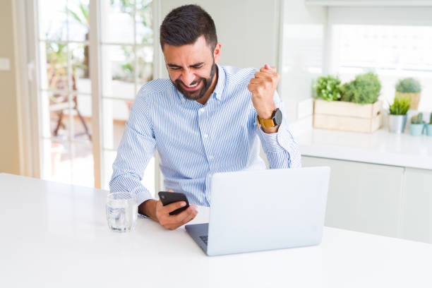 istock Handsome hispanic business man using laptop and smartphone annoyed and frustrated shouting with anger, crazy and yelling with raised hand, anger concept 1139067590