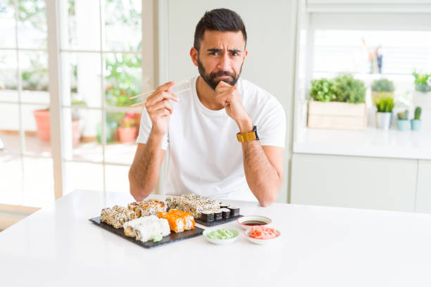 istock Handsome hispanic man eating asian sushi using chopsticks serious face thinking about question, very confused idea 1139068058