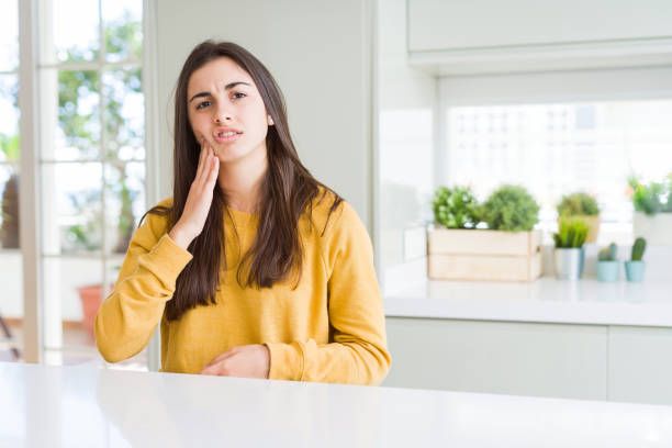 beautiful young woman wearing yellow sweater touching mouth with hand with painful expression because of toothache or dental illness on teeth. dentist concept. - dentist pain human teeth toothache imagens e fotografias de stock