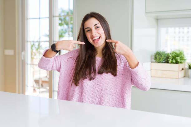 Beautiful young woman wearing pink sweater smiling confident showing and pointing with fingers teeth and mouth. Health concept. Beautiful young woman wearing pink sweater smiling confident showing and pointing with fingers teeth and mouth. Health concept. pakistan photos stock pictures, royalty-free photos & images