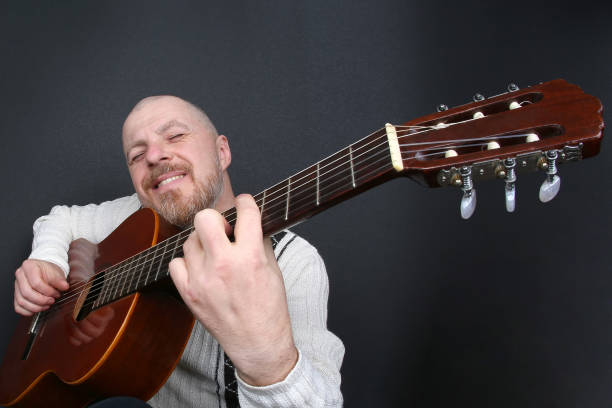 istock bearded bald man plays classical guitar 1139070560