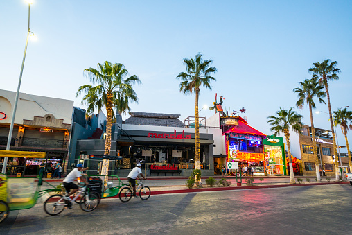 Cabo San Lucas, Mexico - January 12, 2018: Shops and restaurants full of tourists in Cabo San Lucas. Pedicabs moving on the street