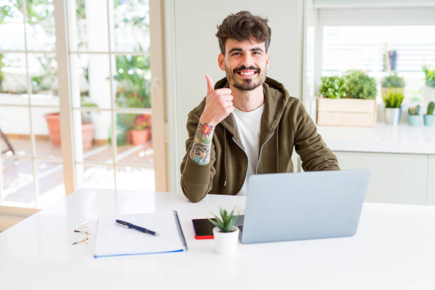 istock Young student man using computer laptop and notebook happy with big smile doing ok sign, thumb up with fingers, excellent sign 1139073772