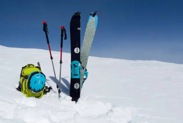Splitboard halves, trekking sticks and backpack at sky background with copy-space. Ski touring equipment and accessories