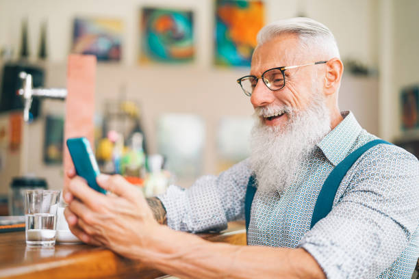 istock Hipster man using mobile phone while sitting in a bar - Senior male watching on new trends smartphone apps for social media - Technology and people lifestyle concept 1139078395