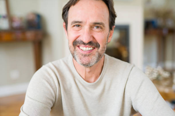 istock Handsome middle age man sitting on the floor smiling at the camera at home 1139078469