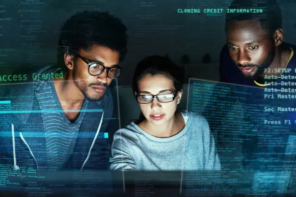 Shot of a group of programmers working on  computer code at night