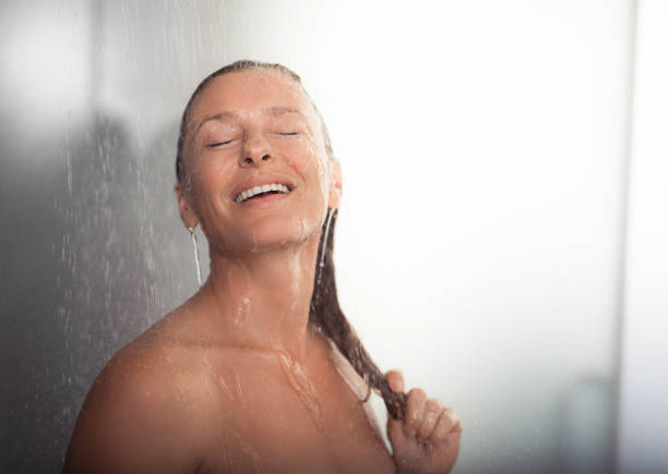 istock Cheerful middle aged woman touching hair while taking shower 1139081419