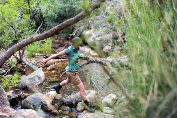 istock Female explorer jumping over rocks in riverbed 1139082290