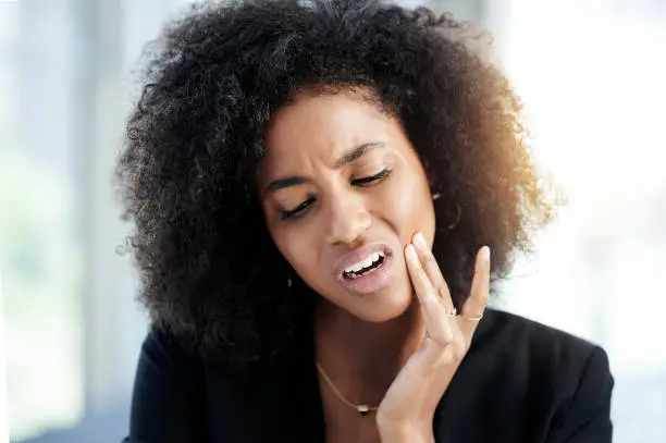 Shot of a young businesswoman suffering from toothache at work