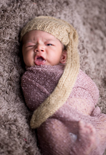 Adorable newborn baby boy wrapped in fur blanket