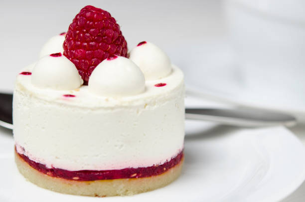 istock White airy cake with raspberry layer and raspberry berry lies on a white round plate next to a white cup, which stands on a white table 1139084230