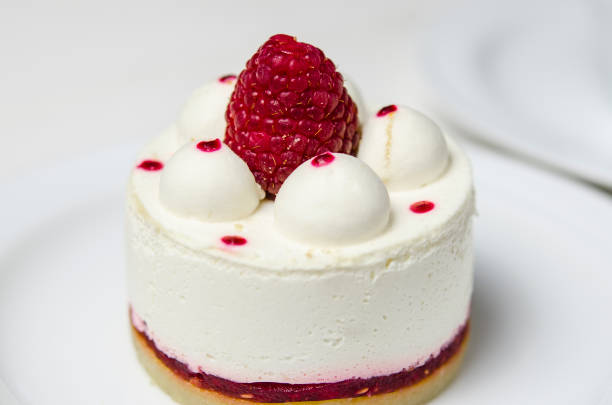 istock White airy cake with raspberry layer and raspberry berry lies on a white round plate next to a white cup, which stands on a white table 1139084239